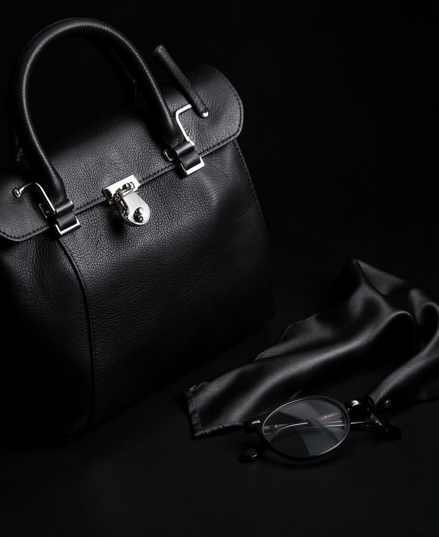 Black leather handbag with silver hardware, silk scarf and glasses
